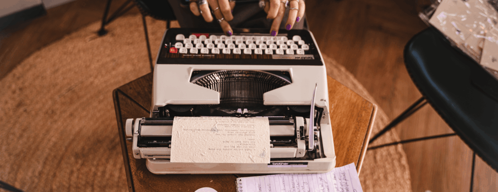 hands with purple fingernails typing on a typewtiter
